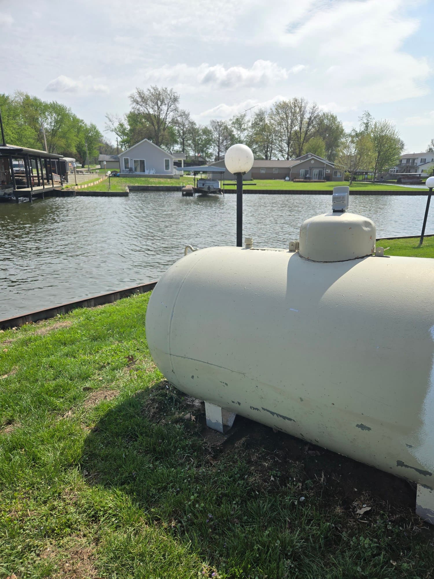 Lakefront property with freshly mowed grass around a propane tank — waterfront lawn care by Jarjus Lawn Care
